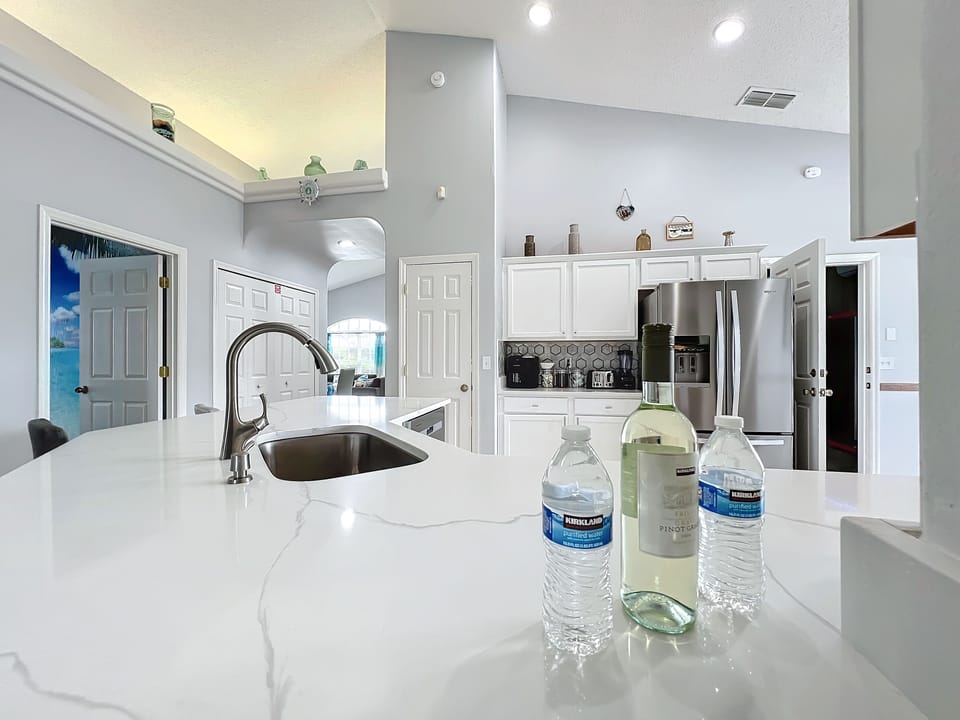 - Large quartz island with built in sink & extra seating for casual dining or drinks
- Welcome touches like bottled water & wine make your arrival feel extra special
- Open layout flows seamlessly into living areas, perfect for entertaining & gathering