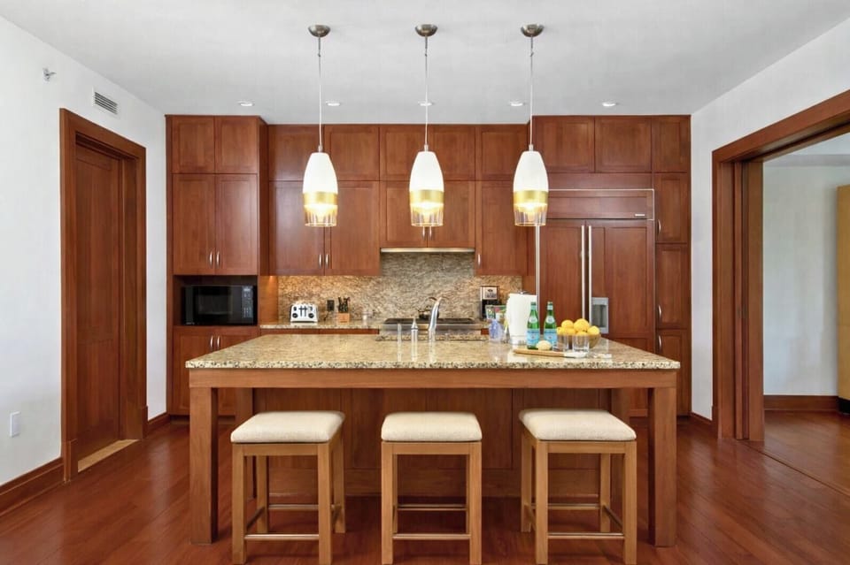 Pendant lighting highlights your expansive kitchen island, with barstools perfectly positioned for coffee or casual meals.