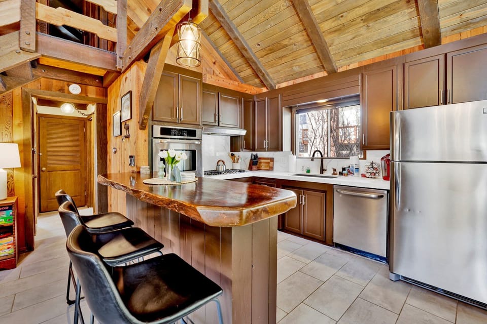 Cozy mountain living room with a stone fireplace, comfy seating, and smart TV—perfect for relaxing evenings, movie nights, and warm cabin vibes after outdoor adventures.