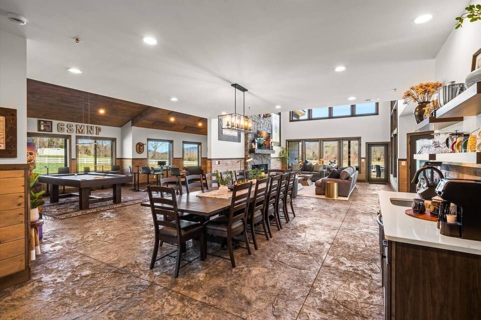 The ultimate open-concept living space: Large chef's kitchen with a spacious island with counter seating, coffee bar by the huge dining table, living room with high ceilings, and of course the bowling/billiards room with arcade games!
