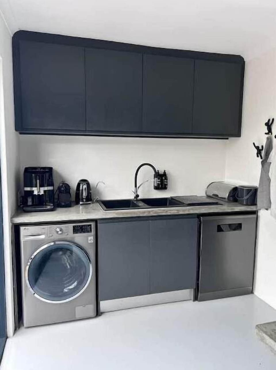 Kitchen area with a sink, washing machine, dishwasher.