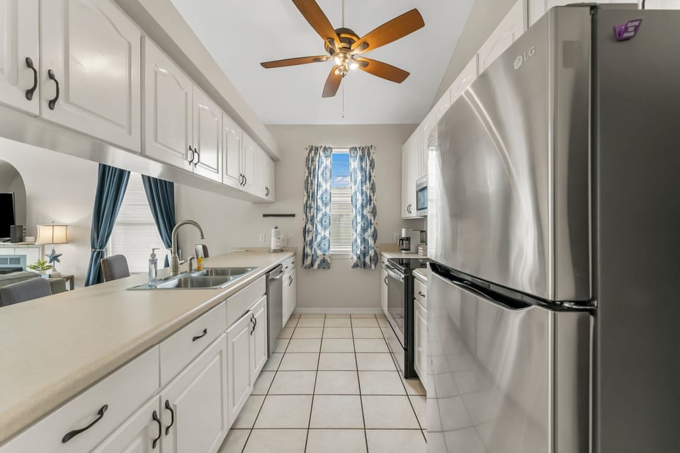 A galley-style kitchen includes full size refrigerator and freezer, dishwasher, electric stovetop and oven, and microwave.