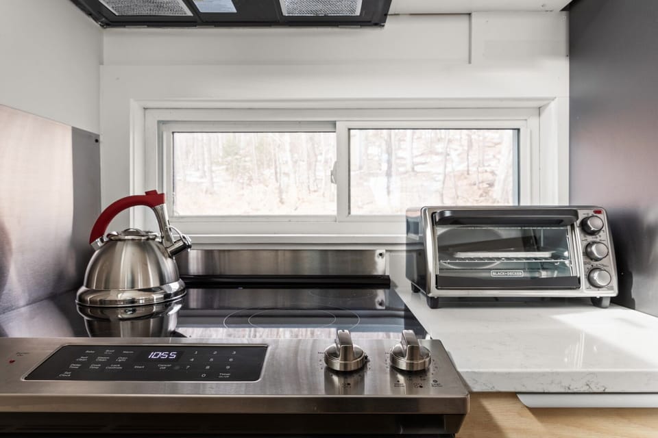 - Sleek stovetop with kettle and toaster oven ready for meal prep   - Airbnb kitchen amenities include cookware for convenient cooking   - Vacation rental provides modern appliances for guest comfort