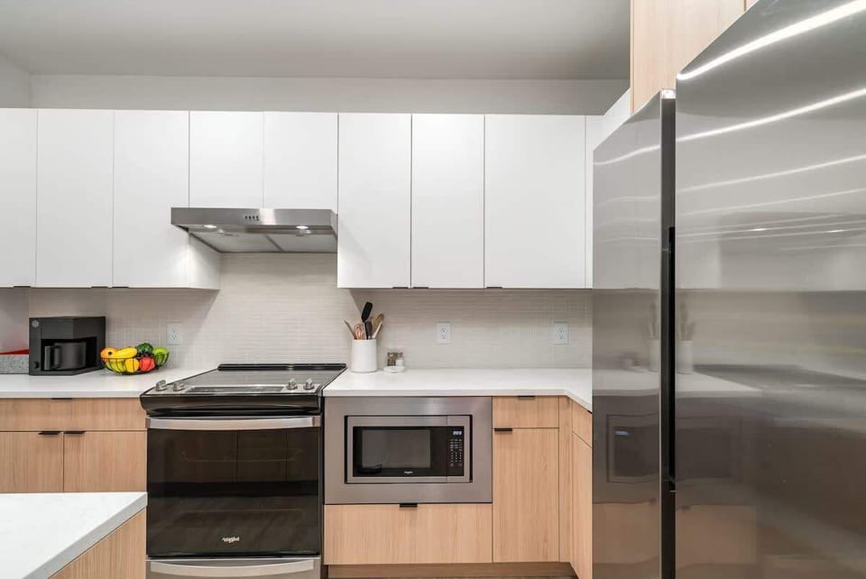 The fully equipped modern kitchen features culinary essentials, stainless steel appliances, and island bar seating.
