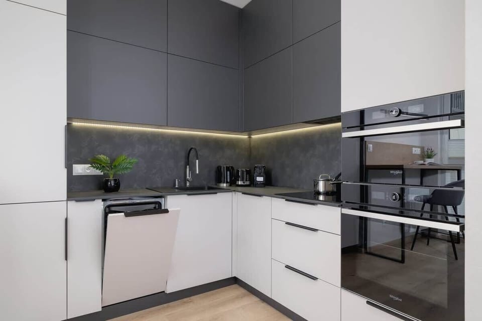A sleek, modern kitchen with black and white cabinets, a built-in oven, and a minimalist design.