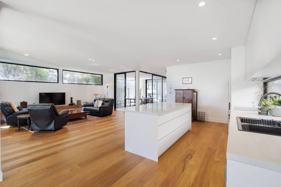 The living and dining area is open plan with large glass windows filling the space with beautiful natural light.
