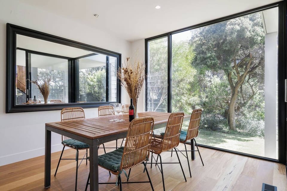 A large dining table allows you to come together for a shared meal, while oversized glass windows create a natural backdrop.
