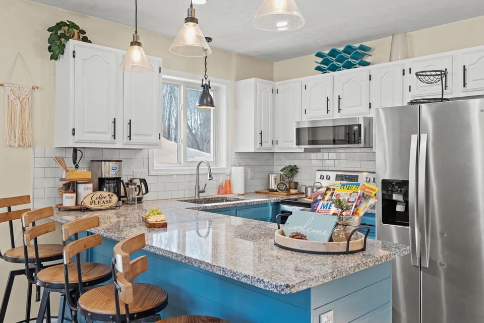 The kitchen features modern, stainless steel appliances and all the cooking essentials provided.