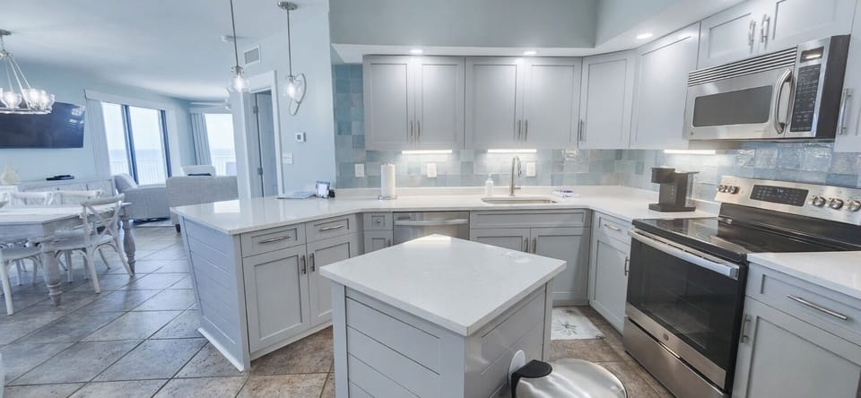 Bright coastal-style kitchen with island, stainless appliances, and open layout