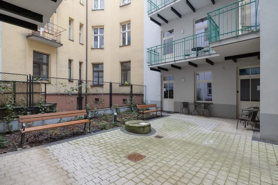 A quiet courtyard with a paved patio, balcony railings, and access to neighboring apartments.

