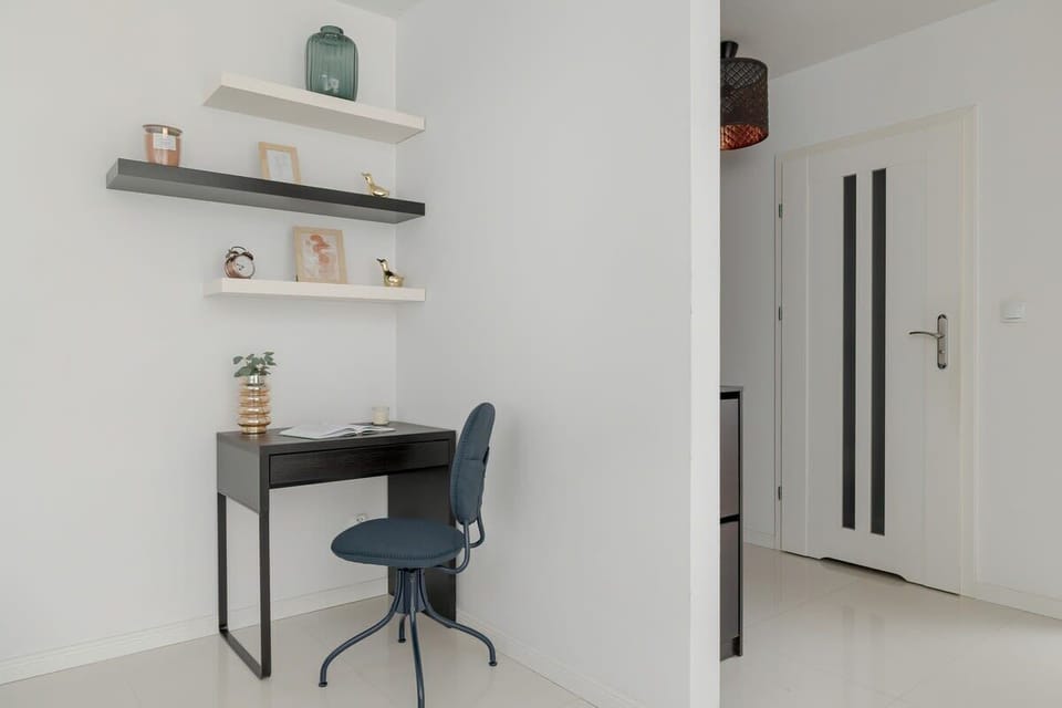 A compact workspace with floating shelves, a black desk chair, and a clean, modern design.

