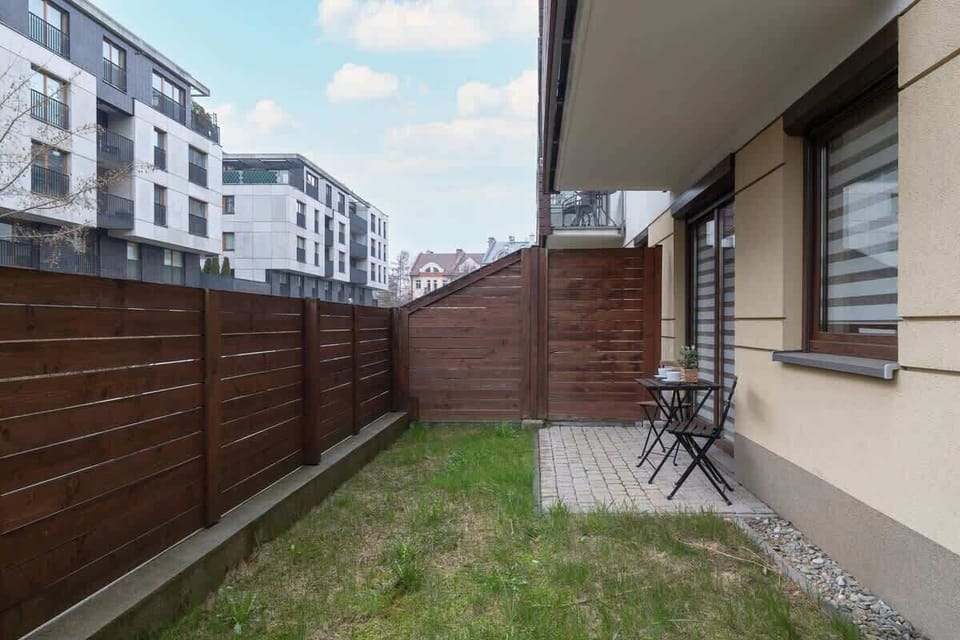 A private outdoor space with a small lawn, a wooden fence, and a cozy seating area, ideal for relaxation.

