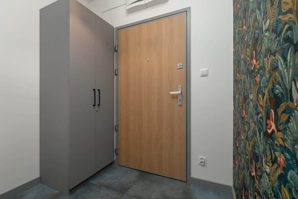 A wooden front door next to which stands a large grey wardrobe. 