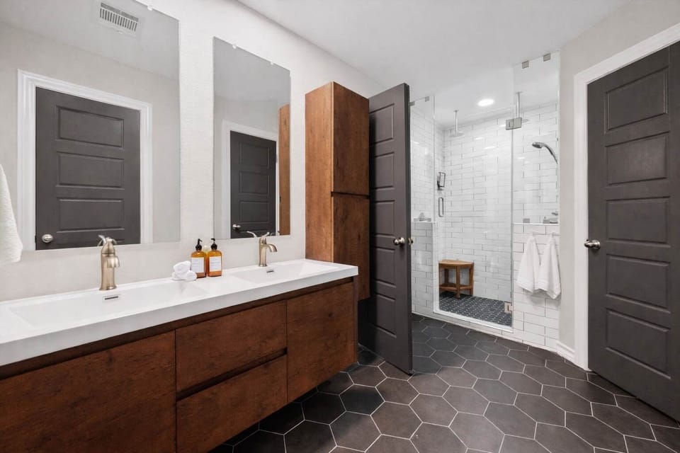 [Bathroom #1] Modern primary bathroom with double vanity and glass walk-in shower.