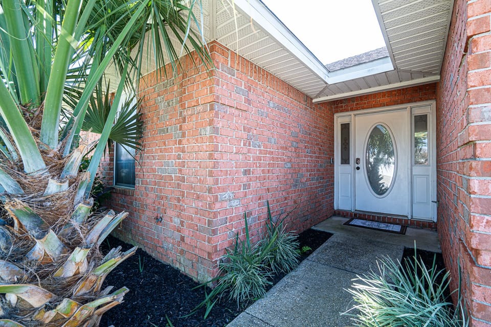 Entryway Delight: Step into your vacation haven with vibrant greenery and inviting brick charm!