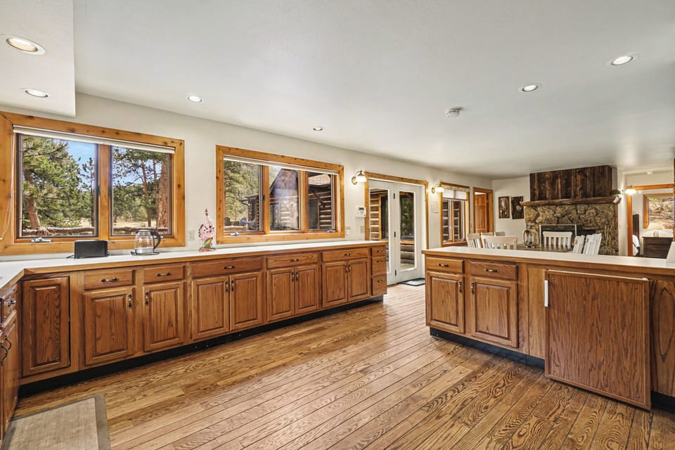 Your spacious kitchen features rich wood cabinets, gleaming countertops, and forest views through large windows for inspiring home-cooked meals.