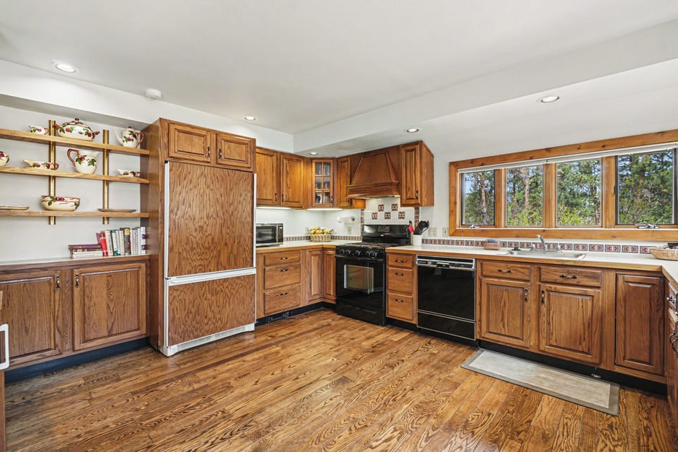 Your spacious kitchen features warm oak cabinets, modern appliances, and charming windows overlooking peaceful trees.