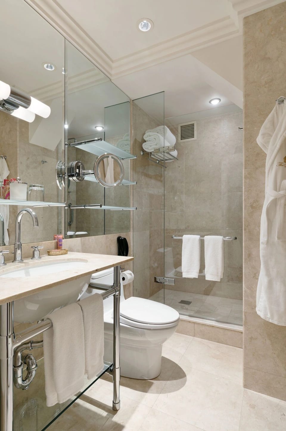 Refresh under bright vanity lights in a spotless marble bath.