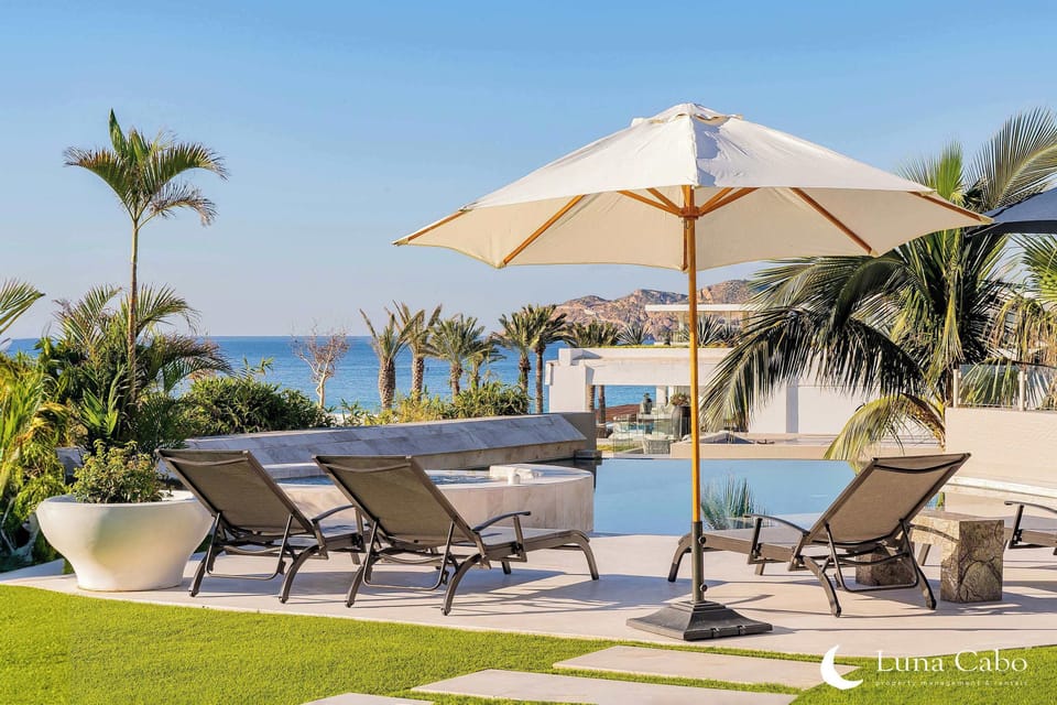 Daytime view of the villa's outdoor area, complete with loungers, pool, and lush landscaping.