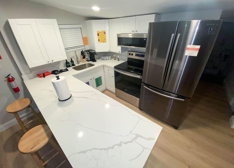 Step into our modern kitchen, a culinary haven with granite countertops, fully stocked with premium kitchenware, a symphony of spices, and stainless steel appliances. Pots and pans await your creativity, while chic bar stools invite conversations. 
