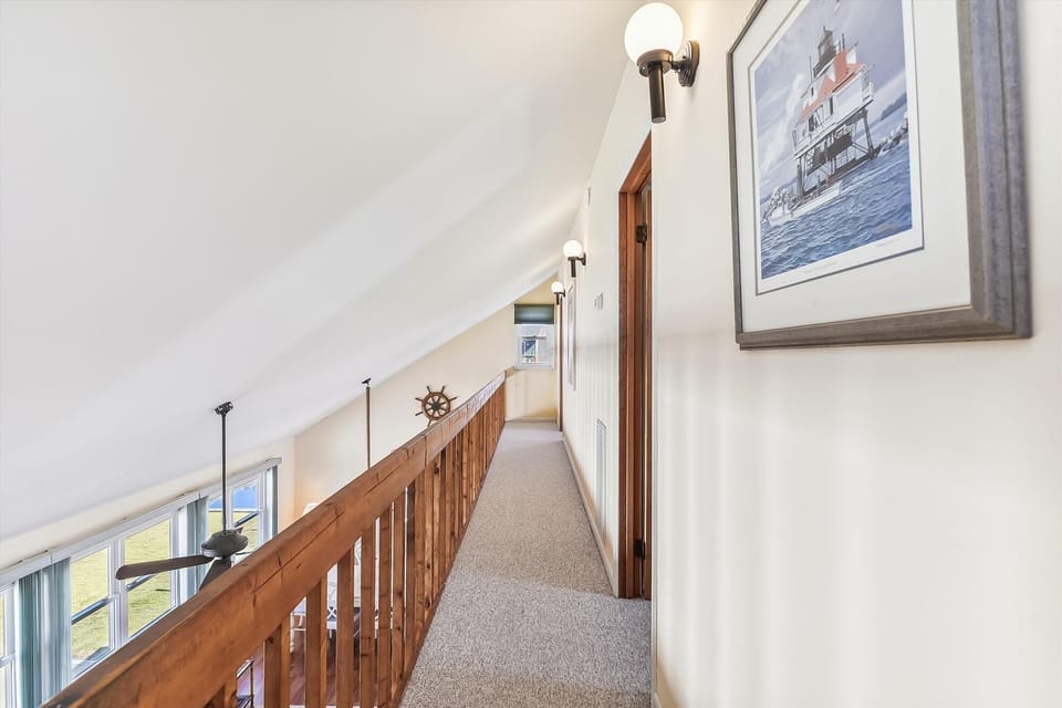 Bright hallway with coastal artwork and warm wood details creates a welcoming path to your private spaces.