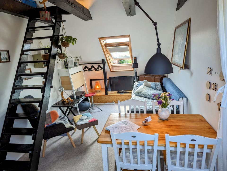 The open room with dining rable, bed, chair and stairs up to the cozy loft.
