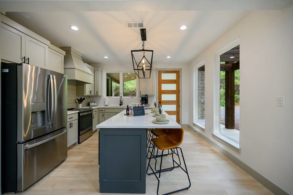 Sleek kitchen with stainless steel appliances, island, and large windows.