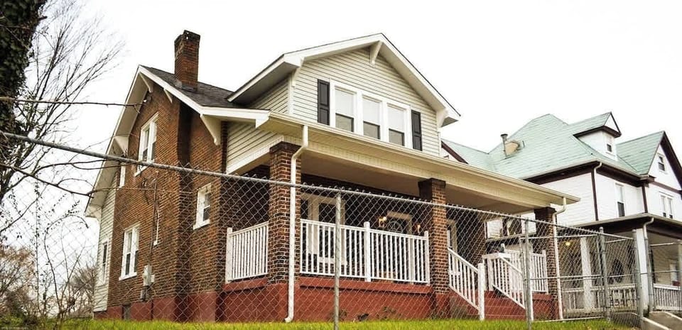 An inviting home, adorned with a charming chain link fence and front steps. Nestled in a prime downtown location, just a minute's drive away, this residence seamlessly combines urban living with cozy comfort—an ideal blend of convenience and allure.