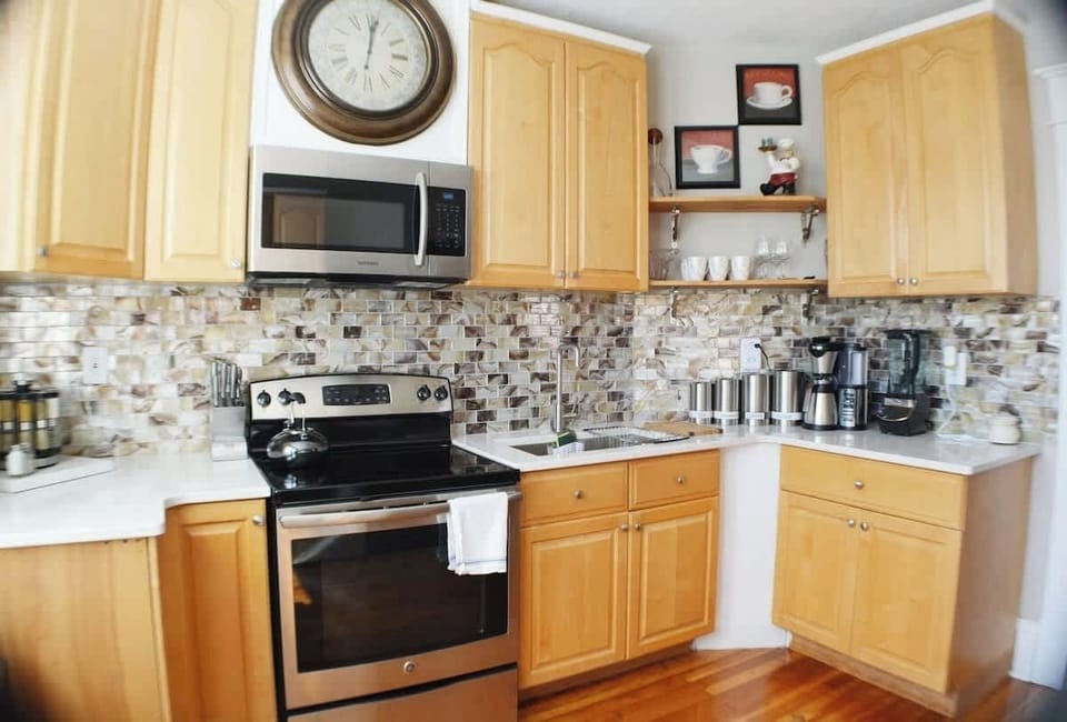 In this kitchen haven, culinary art meets timeless functionality. A wall-mounted clock above the stove adds a touch of classic charm, while an elevated microwave seamlessly blends modern convenience with tasteful design.