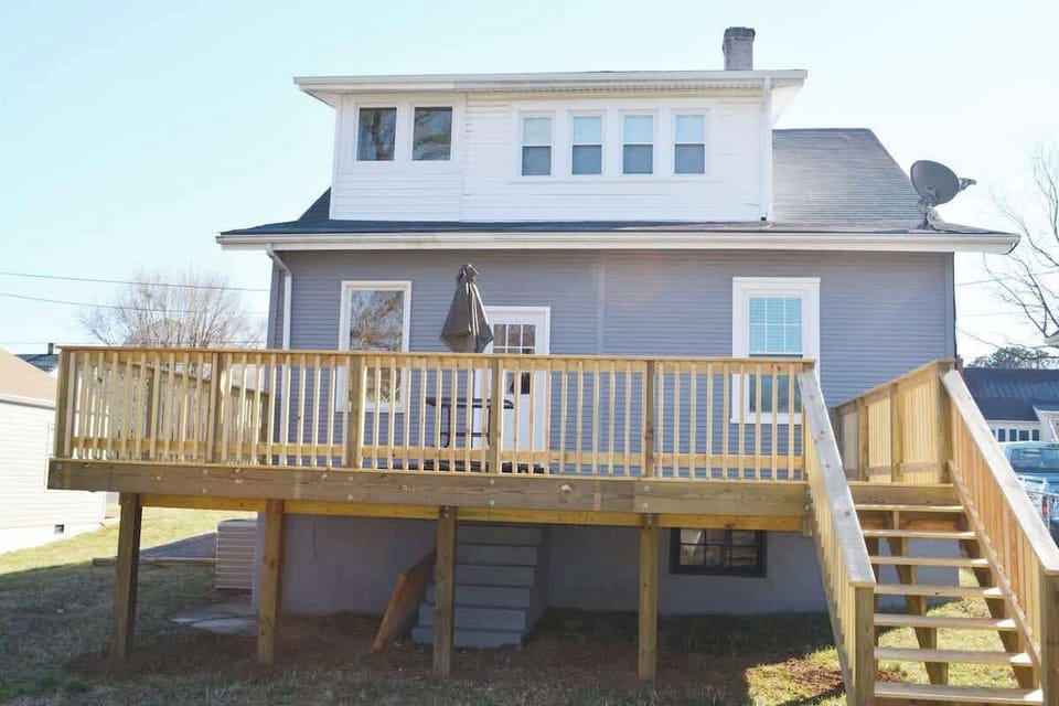 Elegance unfolds in this charming home, where a welcoming deck complements stairs leading to the front door. 