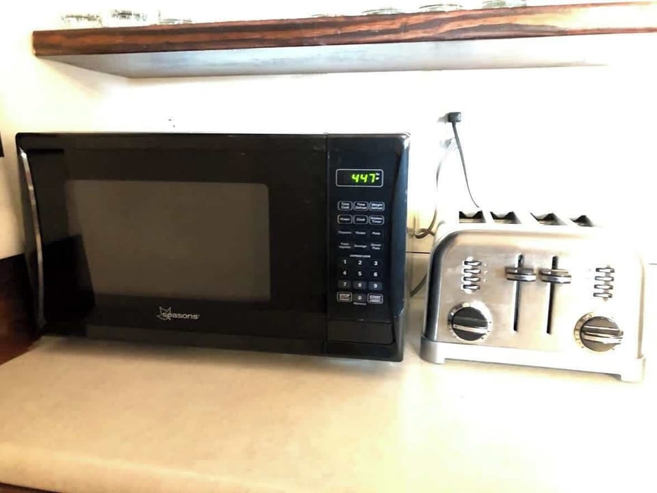 A chic black microwave graces the countertop, keeping company with a pair of trusty toaster ovens, all set to make your kitchen a hub of convenience and deliciousness!