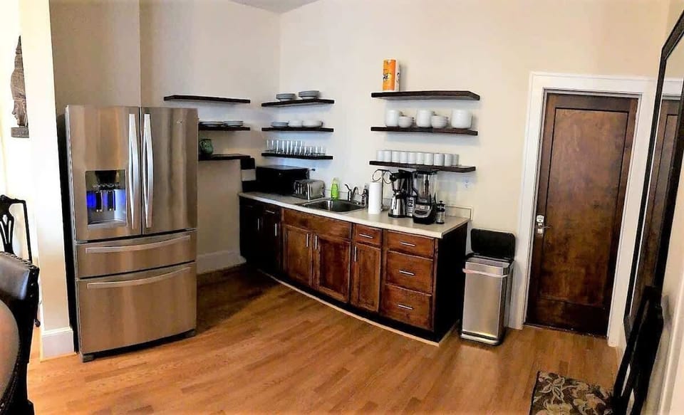 In a cozy kitchen, a gleaming metallic refrigerator-freezer stands tall, its sleek design complemented by a countertop oven and another fridge-freezer, ready to make your culinary adventures come to life!