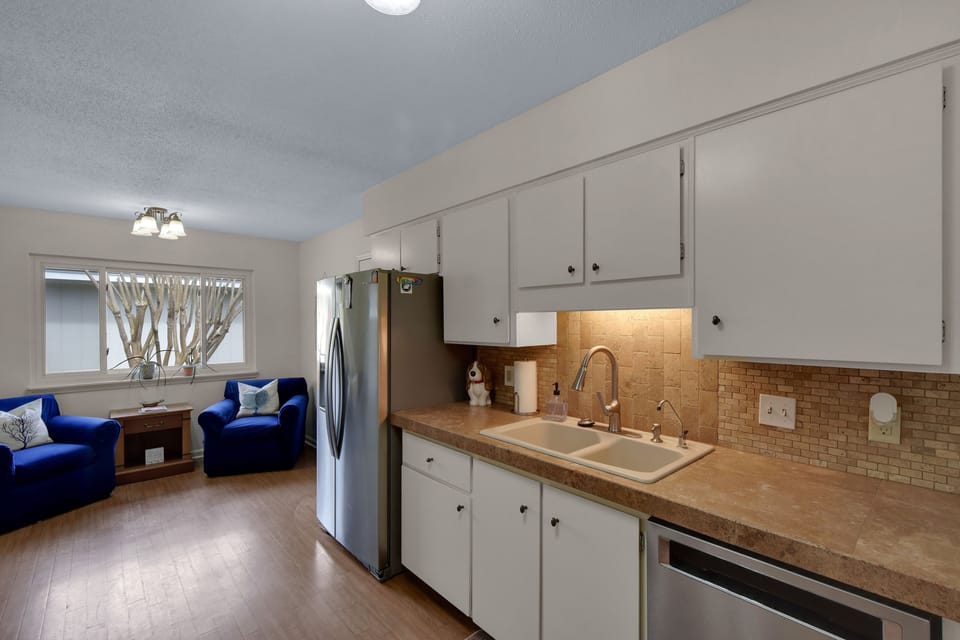 Kitchen – Stainless Steel and Reading Nook Views - A clean, functional kitchen with stainless appliances, clay-tile backsplash, and a surprise bonus—a sunny nook just beyond with twin armchairs for sipping or snacking.