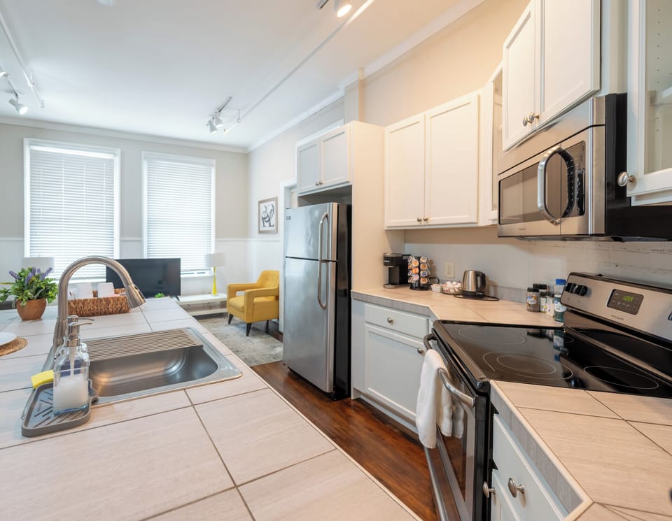 Cook with ease in the fully equipped kitchen featuring stainless-steel appliances, a coffee station, and a bright open layout that connects seamlessly to the living space.