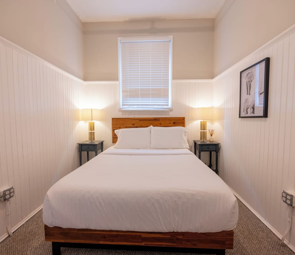 Relax and unwind in the inviting queen-size bed, surrounded by warm lighting and calm, modern décor — the perfect place to recharge after a day exploring Albany.