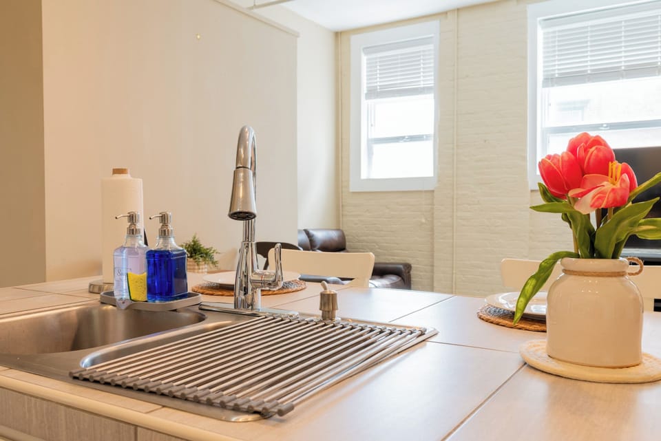 Enjoy the convenience of a modern kitchen island with pull-down faucet, stocked essentials, and a cozy dining setup.
