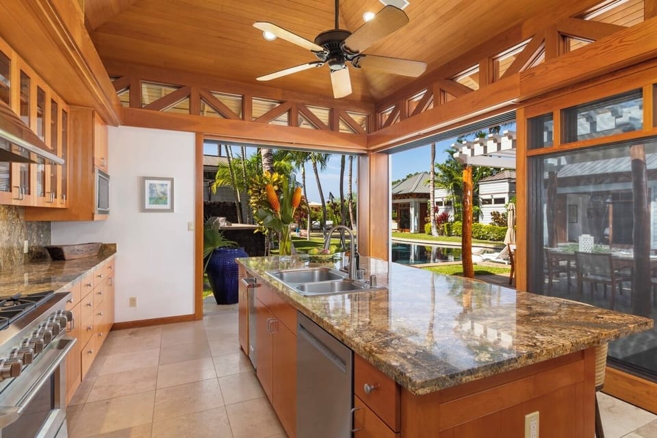 The kitchen, a gourmet's dream featuring granite countertops, a spacious island, and premium appliances, including a 6-burner gas stove.