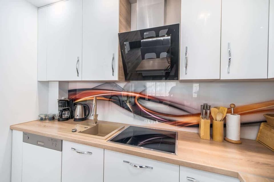 A modern kitchen with white cabinetry, built-in appliances, and a wooden backsplash for a stylish touch.

