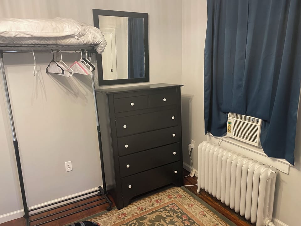 Dresser and extra hanging rack with extra blanket and pillow. Blackout curtains.