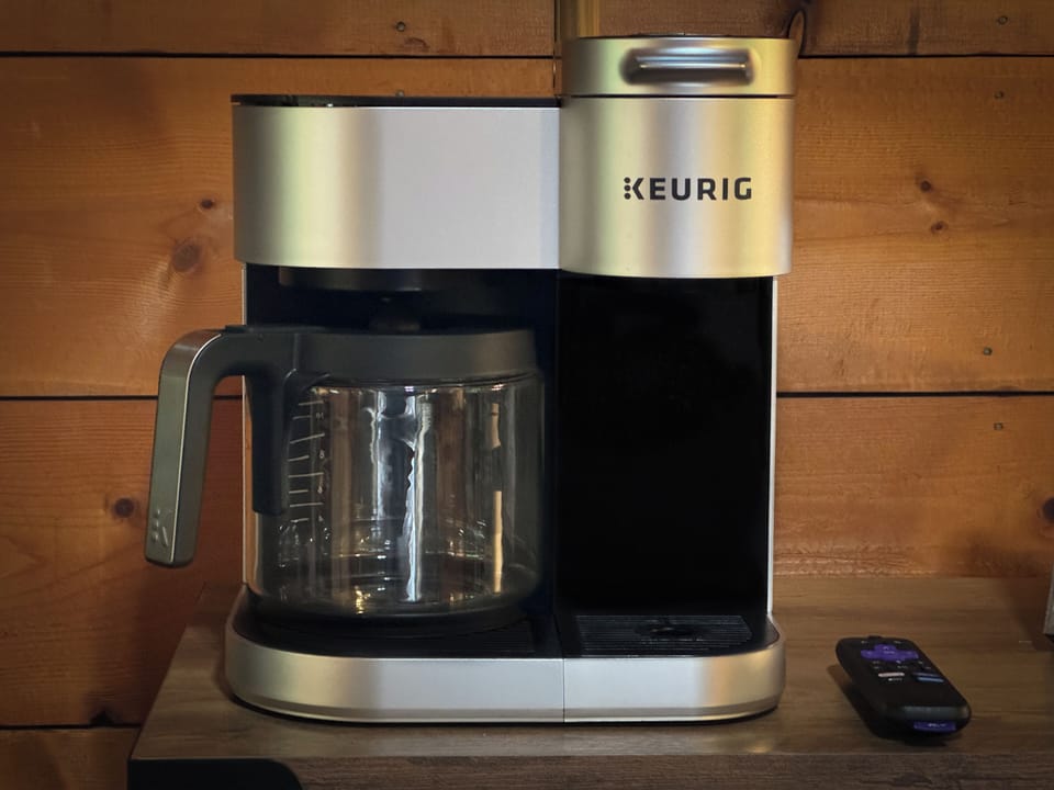 Duo Keurig coffee maker, coffee grounds, and a few coffee pods are provided. 