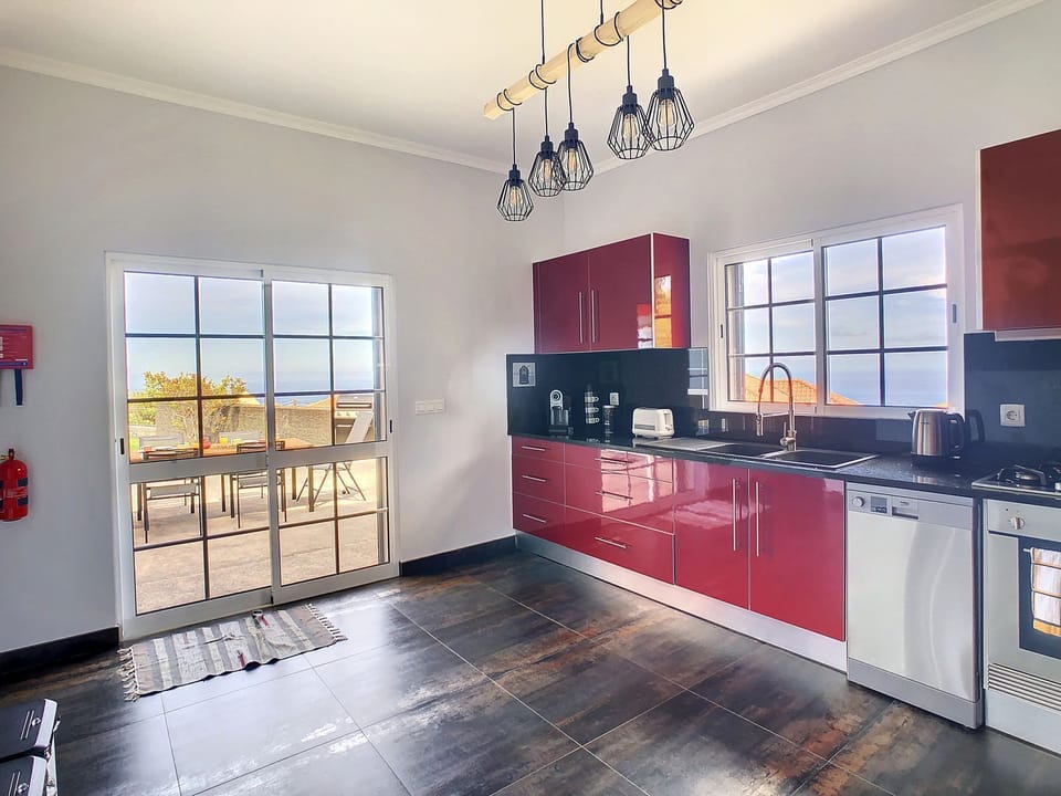 Our kitchen boasts a modern design #red #oceanview #outdoor #decor #coffeemachine