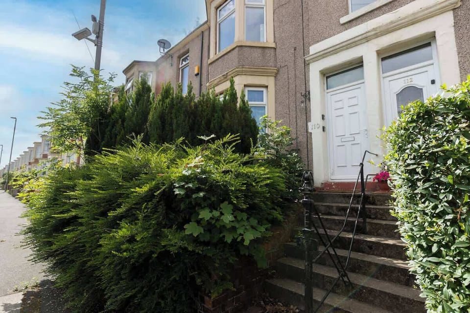 A welcoming entrance surrounded by greenery, with steps leading up to the property.