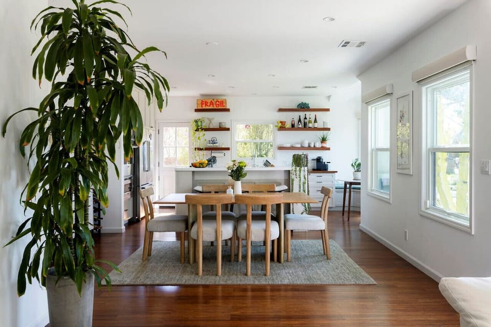 A stylish and inviting dining space featuring a warm wood 6-seat dining table, complemented by additional bar seating for a seamless blend of comfort and functionality.