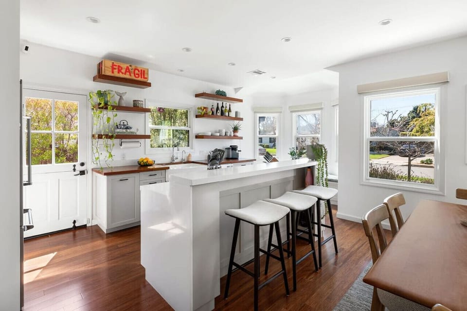 A bright and inviting space featuring a beautifully equipped kitchen with sleek countertops, open shelving, and a stylish bar area perfect for casual dining and entertaining.
