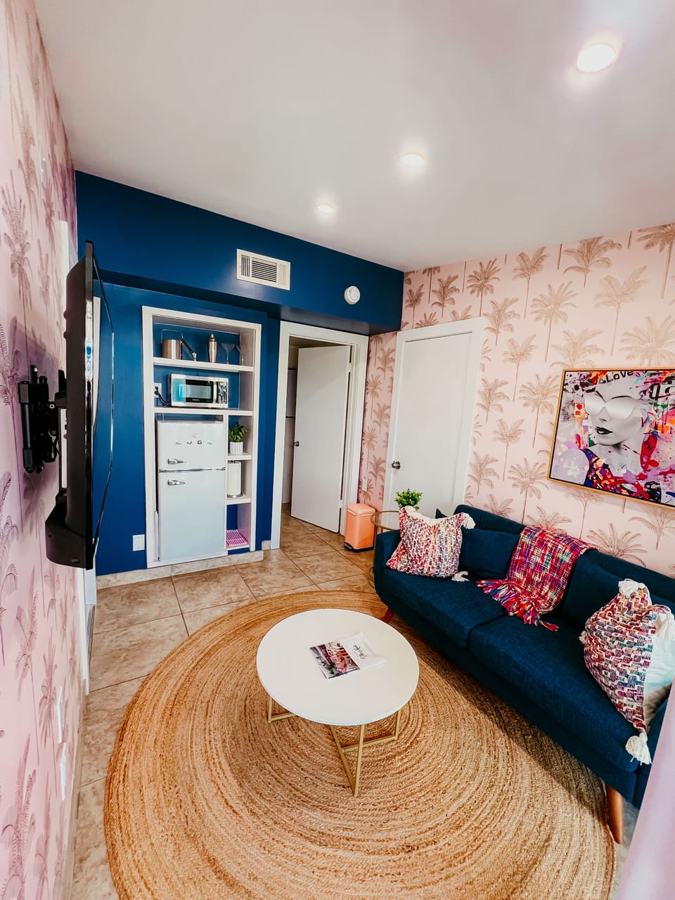 Styled for Fun: Your colorful Palm Springs retreat awaits! Enjoy chic decor, a cozy velvet couch, and essential amenities tucked neatly into a built-in shelf.