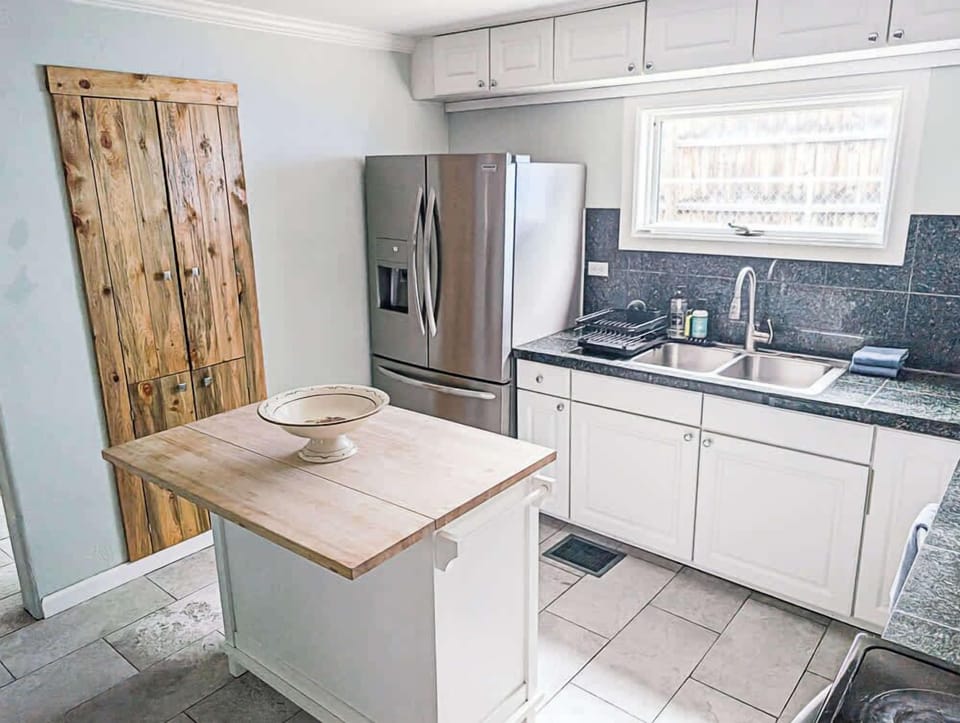 White cabinets with a matching island and light wood countertop.