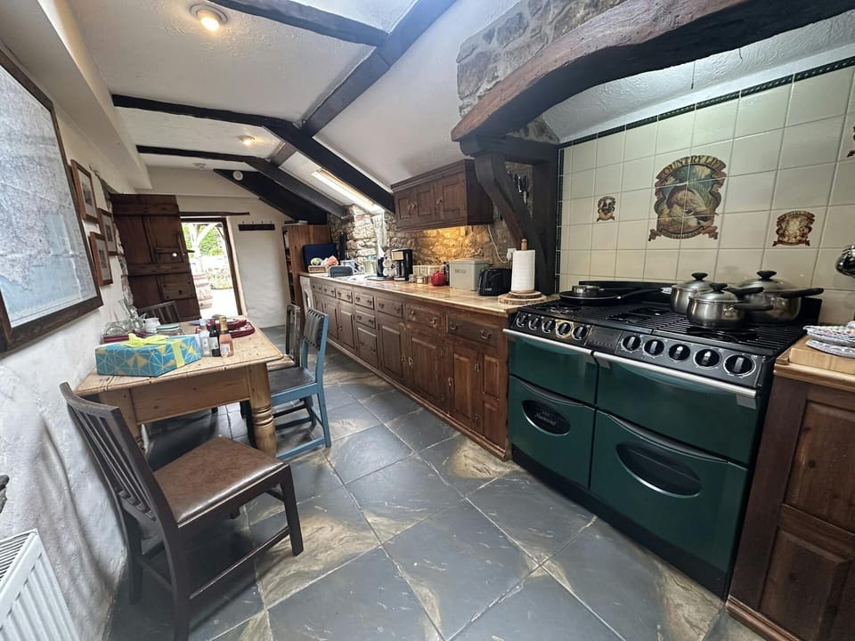 Kitchen with range of kitchen units, washing up sink, stove, dining table and chairs