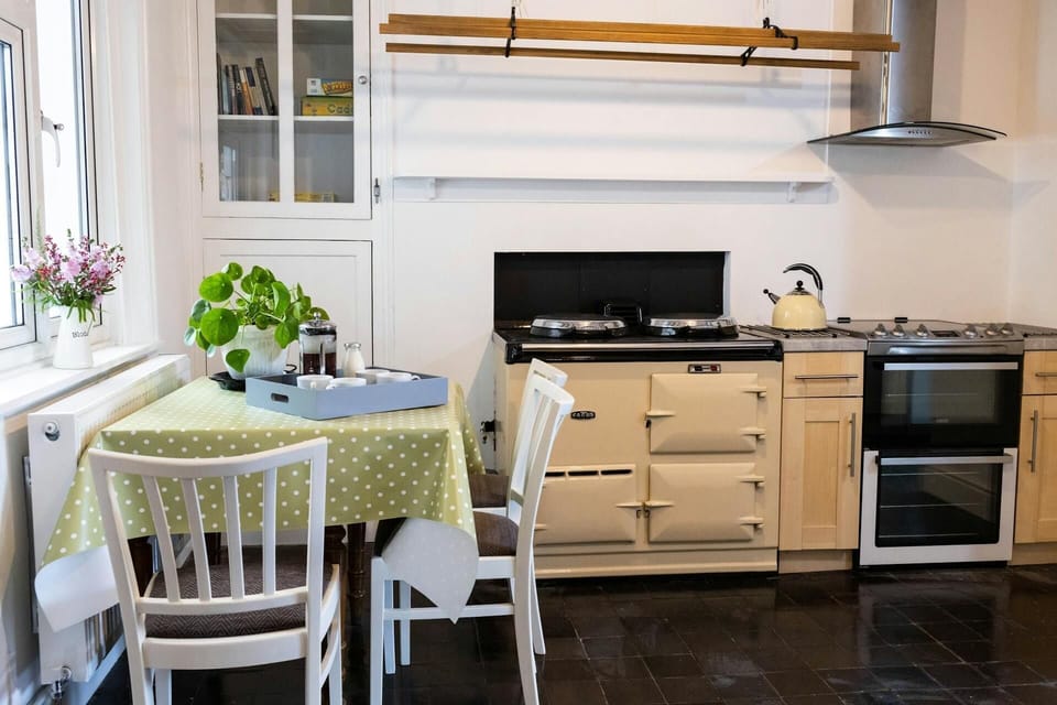 The kitchen with the aga, a table and 3 chairs with a slate floor