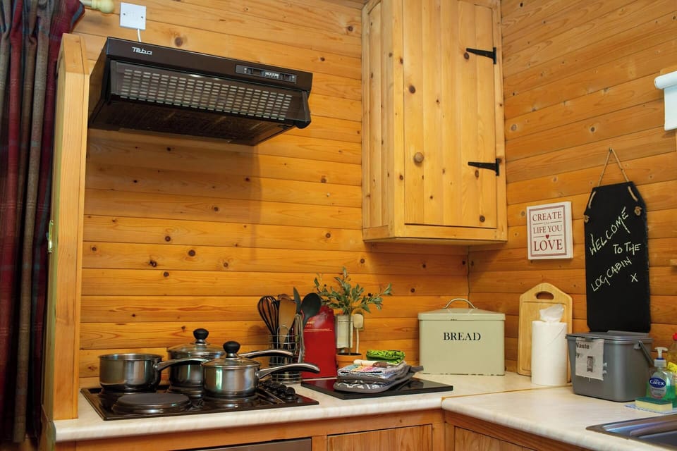 cooker hob with pans on, extractor fan above, bread bin, utensils. food waste bin