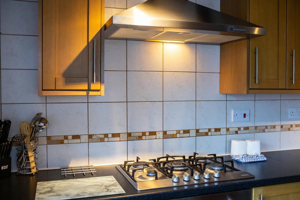 Gas hob and electric oven. Extractor hood with light above. Tiled walls